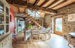 A rustic interior with a wooden staircase, a dining area with striped tablecloths, and a stone wall. - Stunning home in Ploumillau with WiFi (Ploumillau)
