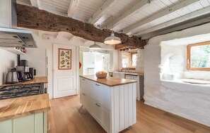 A kitchen with wooden beams, a white door, and a window. - Stunning home in Ploumillau with WiFi (Ploumillau)