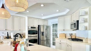 A modern kitchen with white cabinetry, stainless steel appliances, and pendant lighting. - LUX 6BR/3BA Stylish House w/piano, bar, pool&spa (Las Vegas)