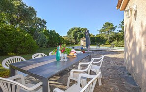 Eine Terrasse im Freien mit Tisch und Stühlen, einer dekorativen Vase und einem kleinen Gebäude im Hintergrund.