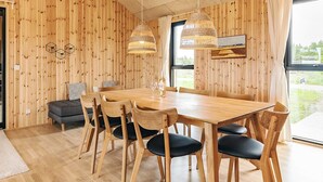 A wooden-paneled room with a dining table, chairs, and a hanging light fixture. - 5 Star Holiday Home in Saltum (Saltum)