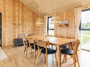 Et rum med træpaneler, et spisebord, stole og en hængende lampe.