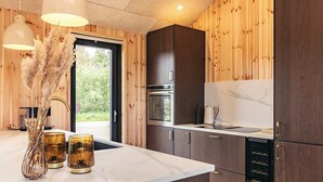 A modern kitchen with wooden paneling, a marble countertop, and stainless steel appliances. - 5 Star Holiday Home in Saltum (Saltum)