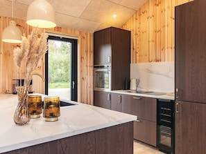 Eine moderne Küche mit Holzvertäfelung, einer Marmorarbeitsplatte und Edelstahlgeräten.