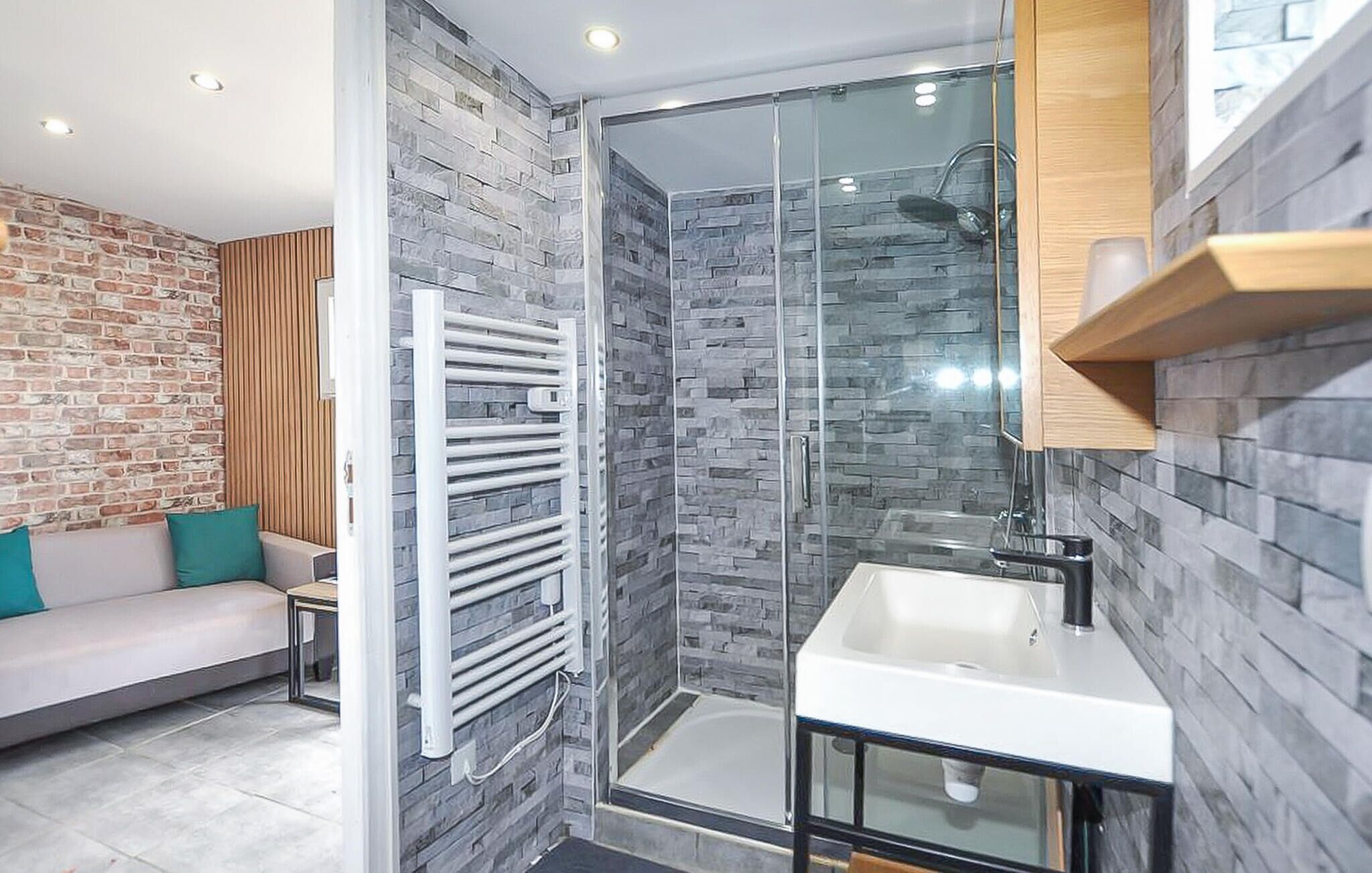 A modern bathroom with a glass shower enclosure, a white sink, and a wooden vanity.