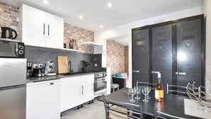 A compact kitchen with a refrigerator, microwave, coffee maker, and a dining area with a table set for two. - 2 bedroom awesome home in Perpignan (Perpignan)