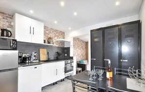 Eine kompakte Küche mit Kühlschrank, Mikrowelle, Kaffeemaschine und einem Essbereich mit Tisch für zwei Personen.