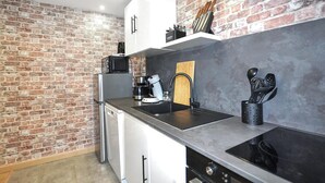 A kitchen with a brick wall, stainless steel appliances, and a modern design. - 2 bedroom awesome home in Perpignan (Perpignan)