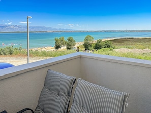 Ein Balkon mit Blick auf Strand und Berge.