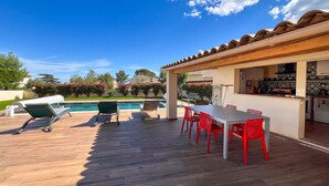 Un patio con piscina, area salotto all'aperto e angolo cottura.