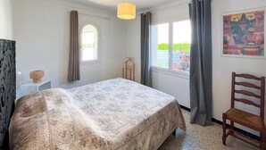 Una camera da letto con un letto, una lampada a sospensione, una finestra e una sedia.