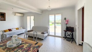 Una stanza con un letto, un tavolo con una ciotola decorativa, un divano e un tavolino con un vaso di fiori.