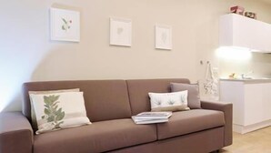 A brown sofa with pillows and a magazine, a white cabinet with items on top, and a tiled floor. - The Seven Ways - Birch Apartment with Relaxing Porch (Piemonte)