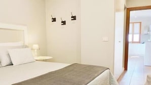 Un dormitorio con una cama, una mesita de noche, una lámpara y una puerta que da a un baño.