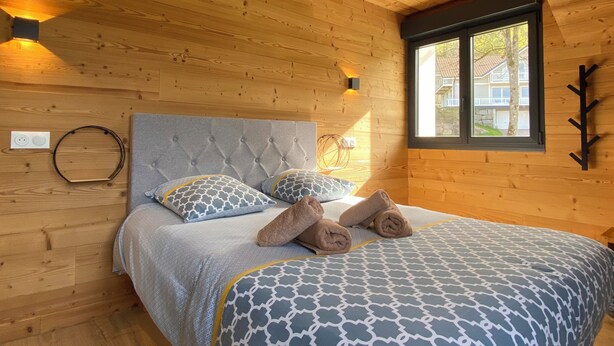 A wooden-paneled room with a bed, a window, and a wall-mounted light fixture. - Les Privilèges family home in the heart of nature, 5 minutes from the town center (Gérardmer)