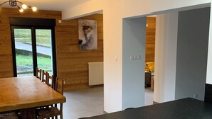 A modern kitchen with a black countertop, white cabinets, and a wooden dining table with chairs. - Les Privilèges family home in the heart of nature, 5 minutes from the town center (Gérardmer)