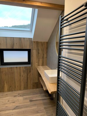 Ein modernes Badezimmer mit Oberlicht, Holzvertäfelung, integriertem Waschtisch und Handtuchhalter.