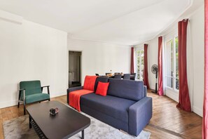 Ein Wohnzimmer mit einer Couch, einem Sessel, einem Couchtisch und einem Ventilator.