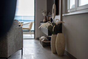 A modern interior with a sofa, two textured vases, and a view of the sea through a window. - Crown Penthouse Čiovo – Luxury 3-Bedroom with Panoramic Rooftop (Okrug Gornji)