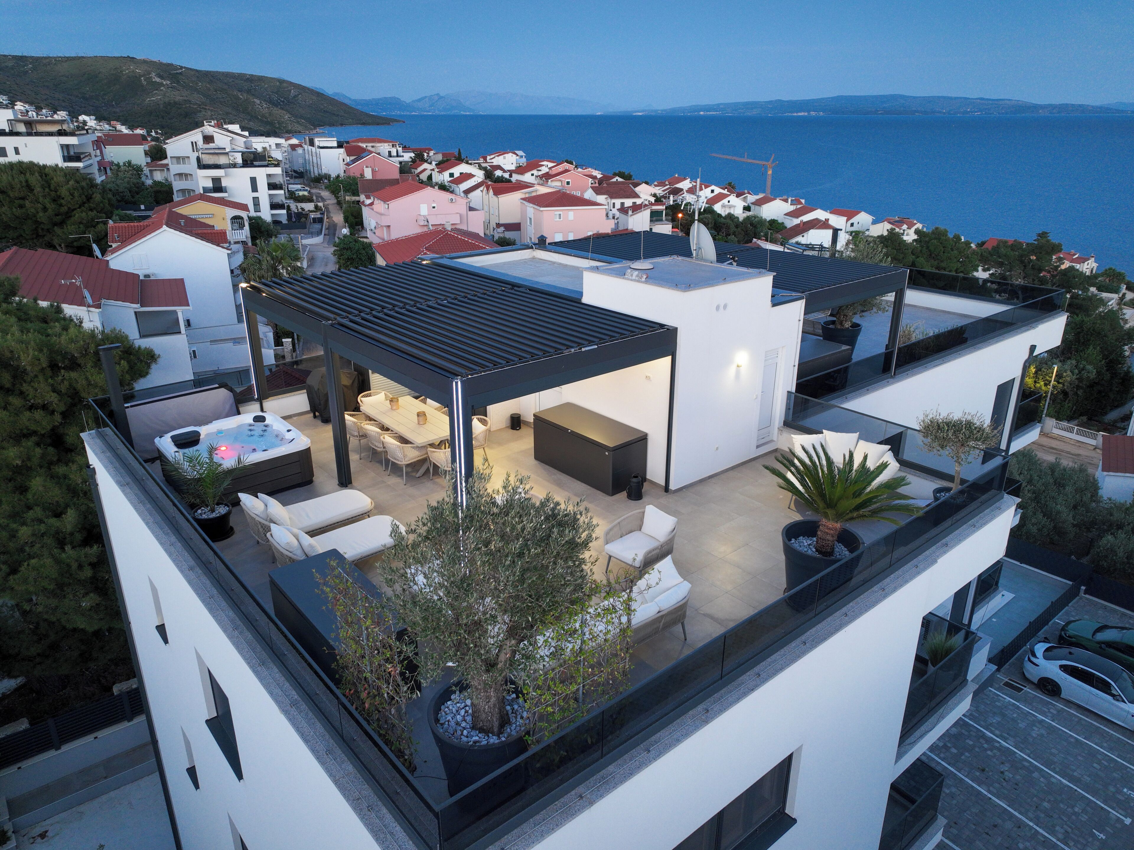 A rooftop terrace with outdoor seating, a hot tub, and a view of the sea.