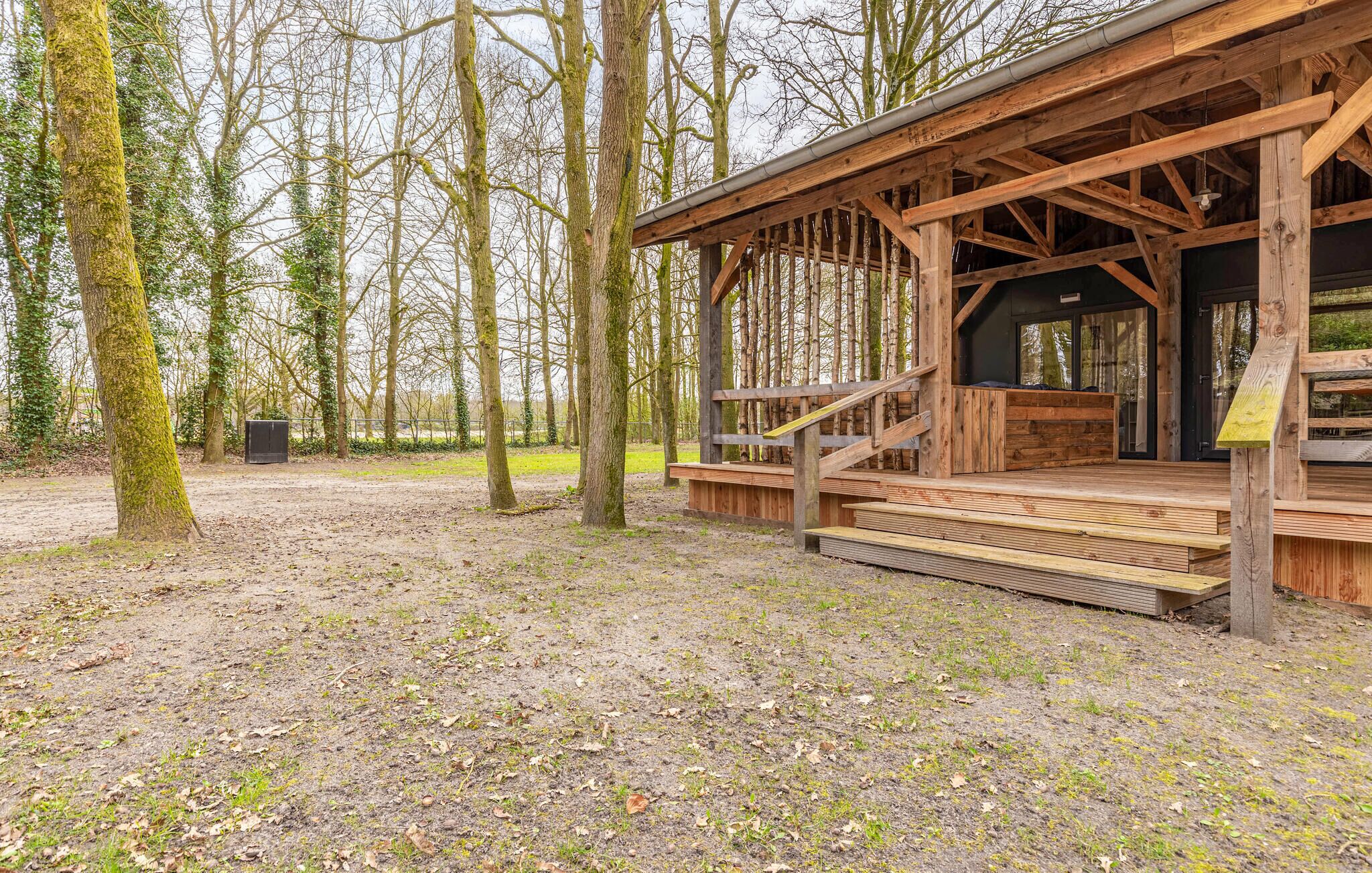 A rustic wooden cabin with a porch, surrounded by trees.