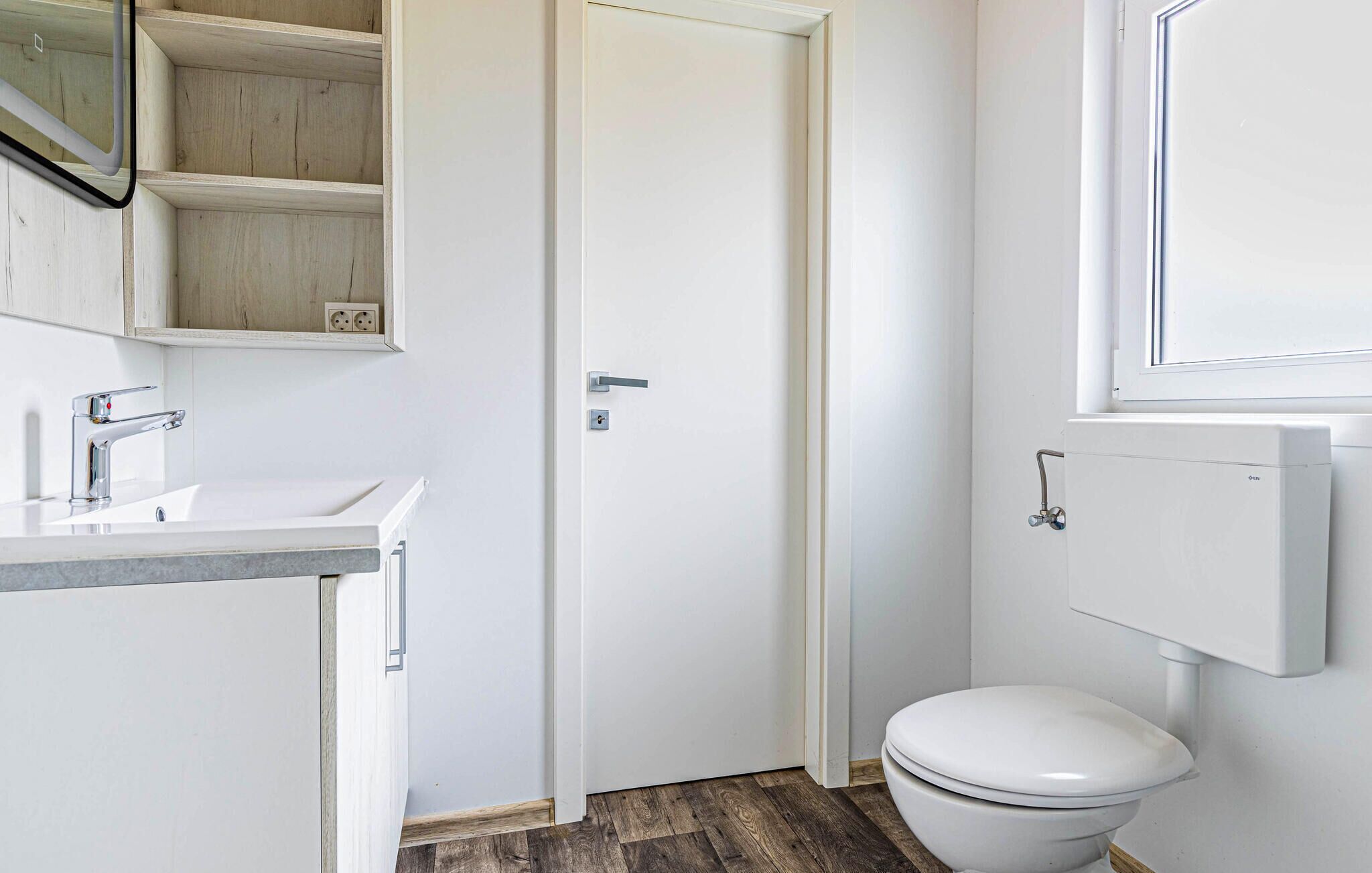 A small, clean bathroom with a white toilet, a sink, and a mirror.