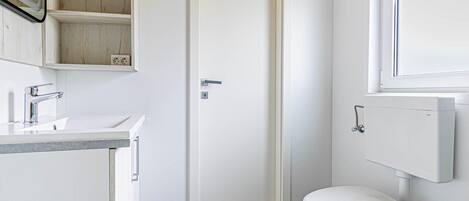 A small, clean bathroom with a white toilet, a sink, and a mirror.