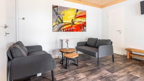 Una sala de estar moderna con dos sofás grises, una mesa de centro de madera y un cuadro abstracto y colorido en la pared.