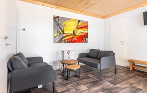 Ein modernes Wohnzimmer mit zwei grauen Sofas, einem Holztisch und einem farbenfrohen, abstrakten Gemälde an der Wand.
