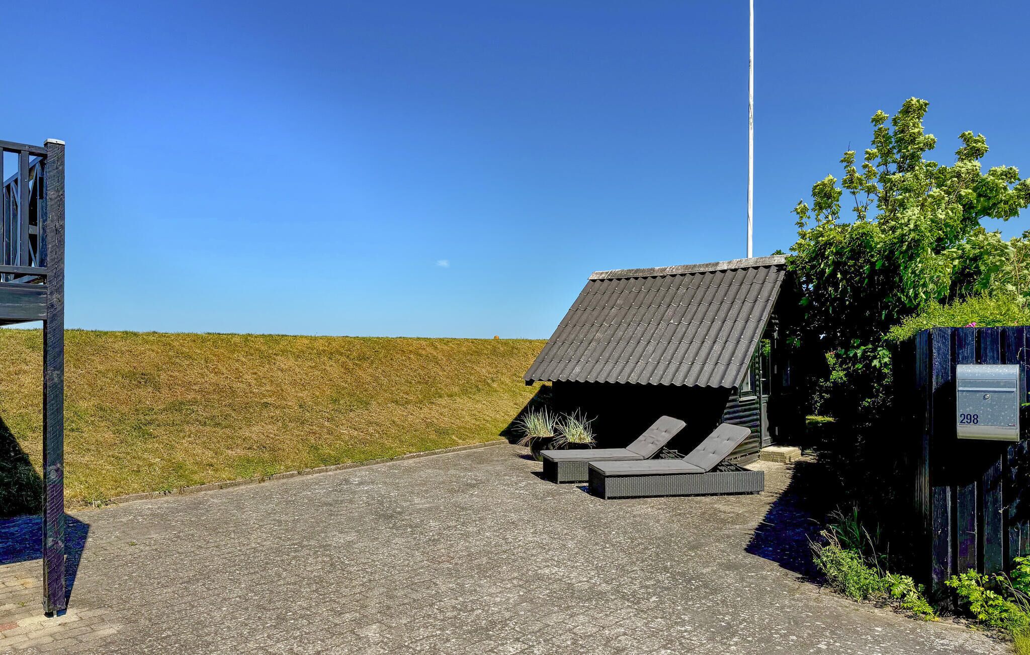 A small building with a sloped roof, two lounge chairs, and a mailbox.