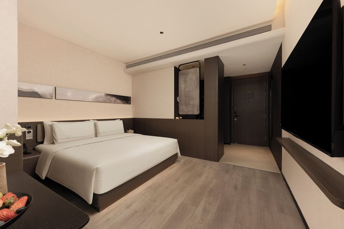 A modern hotel room with a bed, bedside table, and a flat-screen TV.