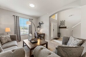 Ein Wohnzimmer mit Sofa, Sesseln und Couchtisch, ein Essbereich mit Tisch und Stühlen sowie eine Treppe zu einer weiteren Ebene.