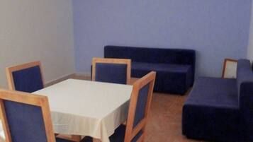 A dining area with a table and chairs, a sofa, and a tiled floor.