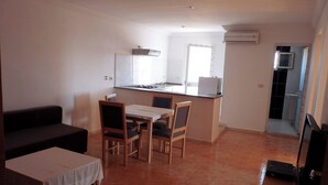 A compact living space with a dining area, kitchenette, and a sofa. - Résidence Le Phare (Djerba Midun)