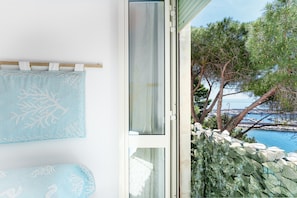 Una stanza con vista sulla costa, una finestra con tenda e un porta asciugamani a parete.
