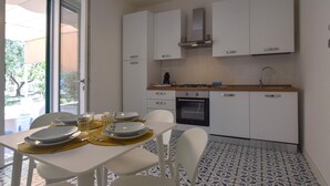 Eine moderne Küche mit weißen Schränken, einem eingebauten Backofen und einem Essbereich mit Tisch für zwei Personen.