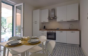 Eine moderne Küche mit weißen Schränken, einem eingebauten Backofen und einem Essbereich mit Tisch für zwei Personen.