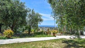 Ein Garten mit einem Pfad, verschiedenen Pflanzen und Blick aufs Meer.