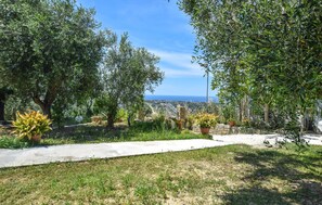 Ein Garten mit einem Pfad, verschiedenen Pflanzen und Blick aufs Meer.