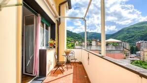 A balcony with a table and chairs, a potted plant, and a view of a mountainous landscape. - 2 bedroom lovely apartment in Genova (Genova)