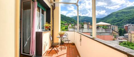Un balcon avec une table et des chaises, un pot de fleurs et une vue sur un paysage montagneux.