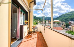 Ein Balkon mit Tisch und Stühlen, einem Blumentopf und Blick auf eine Berglandschaft.