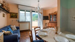A dining area with a table set for four, a chandelier, and a view of mountains through the window. - 2 bedroom lovely apartment in Genova (Genova)