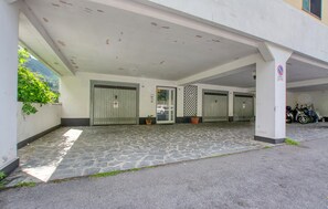 Ein Gebäude mit überdachter Einfahrt, mehreren Eingängen und einem Parkplatz für Motorräder.