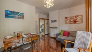Ein Essbereich mit Holztisch und Stühlen, einer Couch und einem Sessel mit Streifenmuster.
