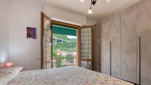 Ein Schlafzimmer mit einem großen Bett, einem Kleiderschrank und einem Balkon mit Blick auf eine Brücke und Gebäude.