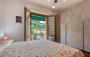 Ein Schlafzimmer mit einem großen Bett, einem Kleiderschrank und einem Balkon mit Blick auf eine Brücke und Gebäude.