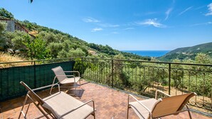 Una terraza con dos sillones de descanso, vista al mar y paisaje verde.