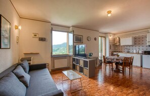 Ein kompakter Wohnraum mit einer Couch, einem Esstisch, einer Küchenzeile und einem großen Fenster mit Blick.