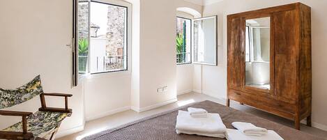 Un dormitorio con cama, armario de madera, una silla y ventana con vistas a vegetación.
